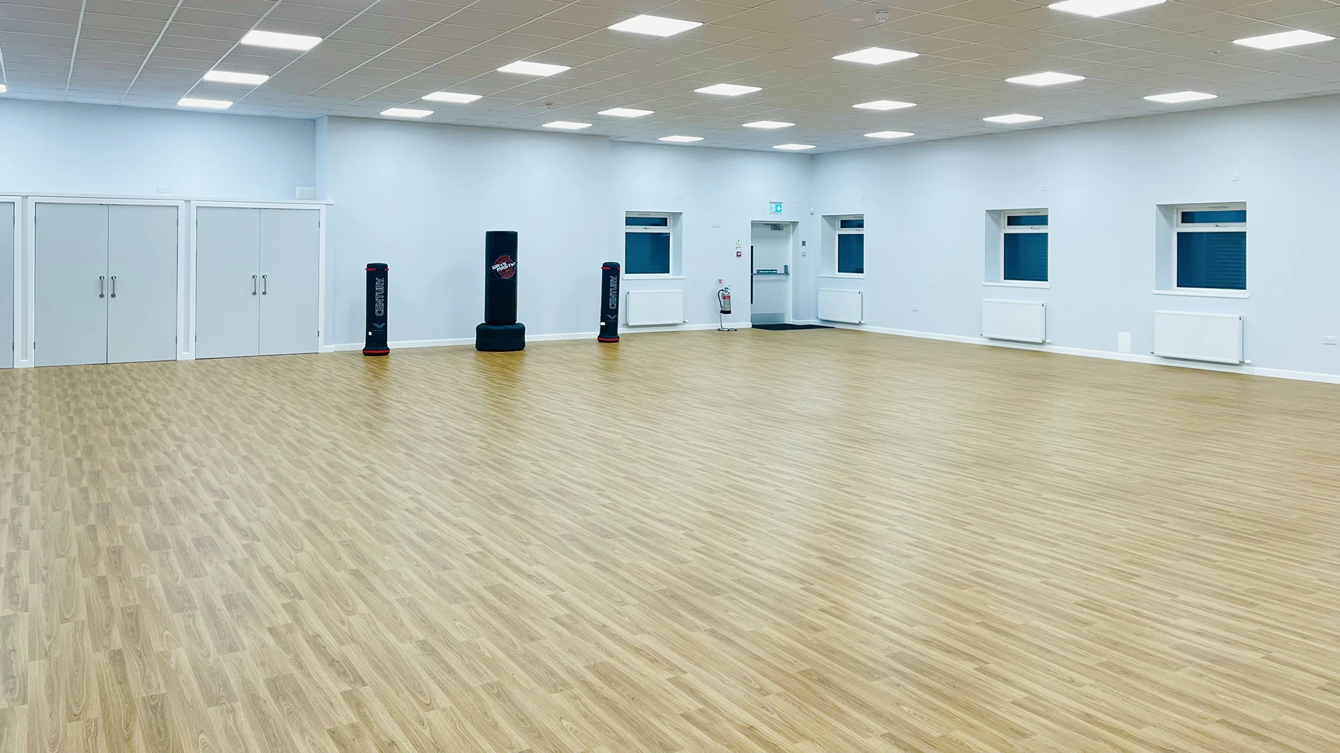 A large bright hall with punch bags along a white wall